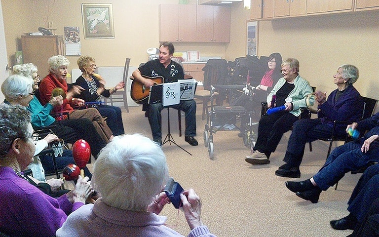 Group of Cardinal Retirement residents singing along to a man playing the guitar