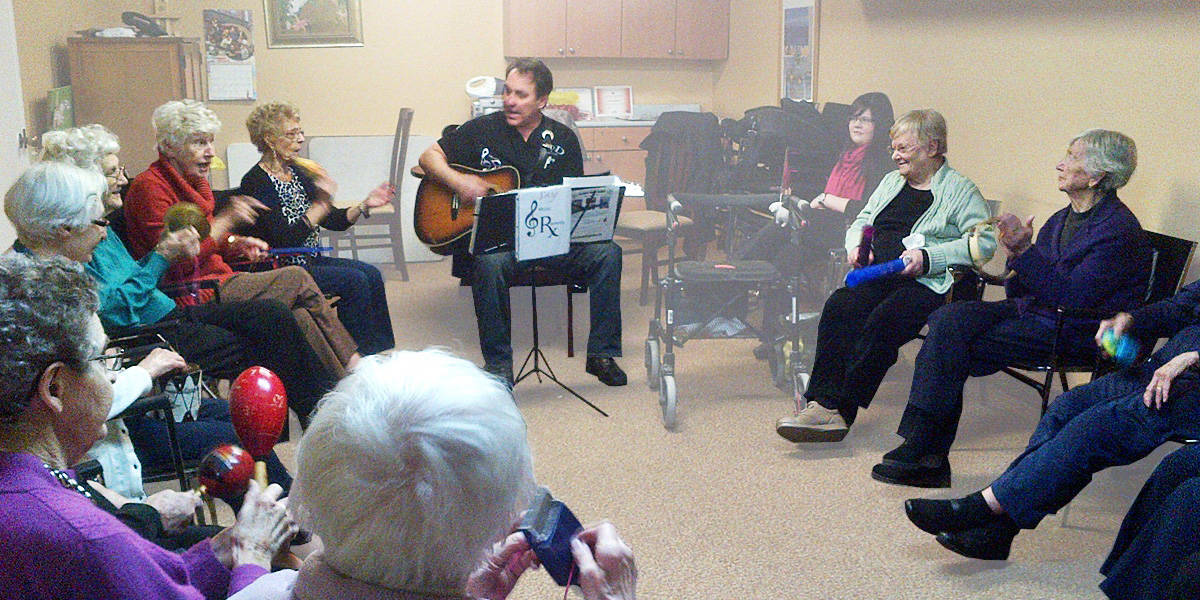 Group of Cardinal Retirement residents singing along to a man playing the guitar