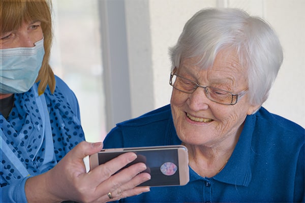 A woman showing a senior a mobile device