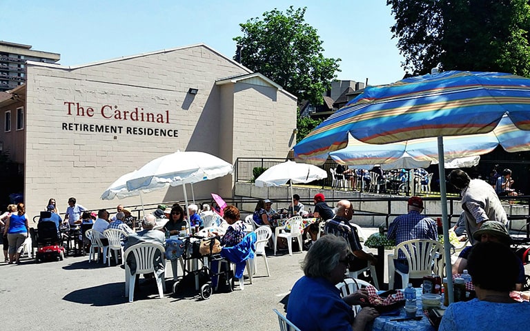About eighty friends from Cardinal Retirement Residence outside, enjoying a sunny day BBQ with their family.